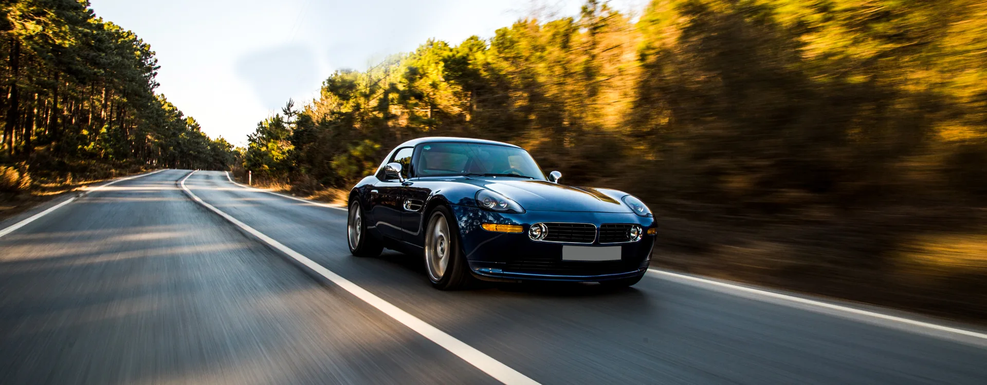 Cabriolet bleu nuit sur une route de forêt