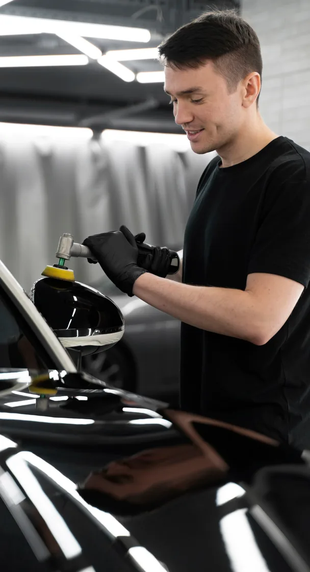 Carrossier polissant la carrosserie d’un véhicule dans l’atelier