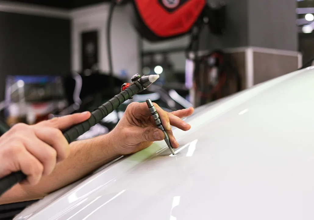 Redressage d’un élément de carrosserie avec un outil de débosselage